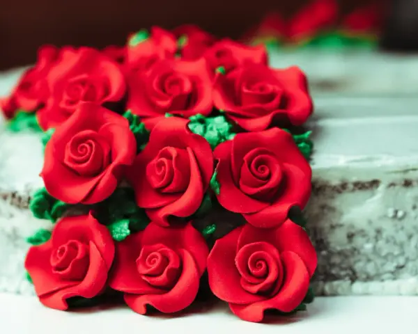 Un mazzo di rose rosse in pasta di zucchero adorna una torta.