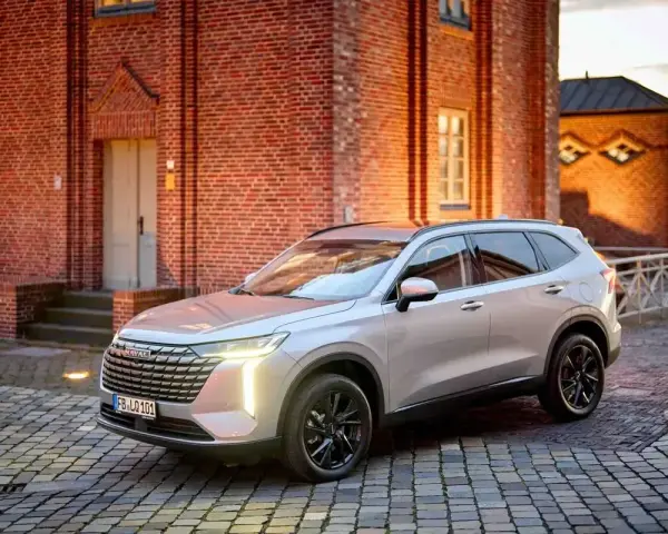 Srebrny Haval SUV zaparkowany na brukowanym dziedzińcu przed ceglanym budynkiem.