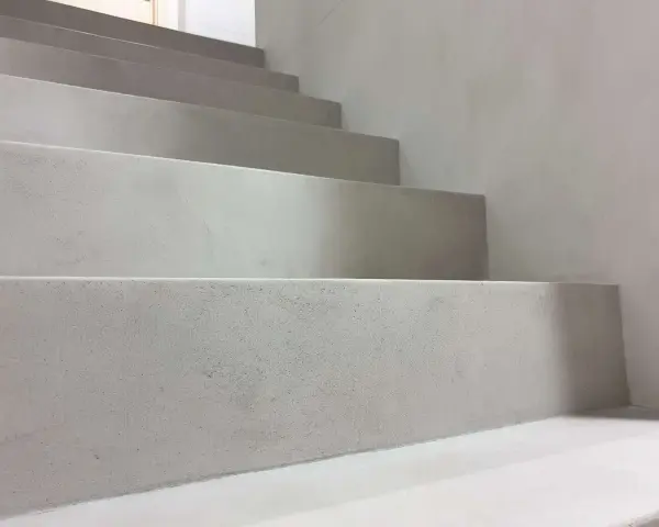 Nowoczesne schody z surowego betonu na klatce schodowej. Minimalistyczny design, jasnoszare stopnie.