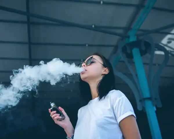 Joven exhala humo de un vaper, una práctica que demuestra que el vaper es malo para la salud.