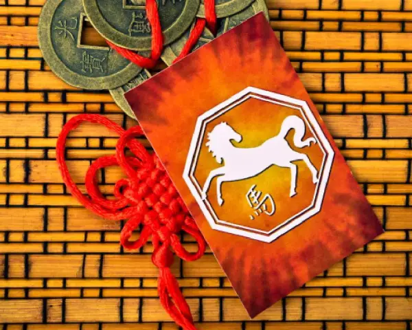 Chiński znak zodiaku 1990 - koń. Obok monety i czerwony sznurek.