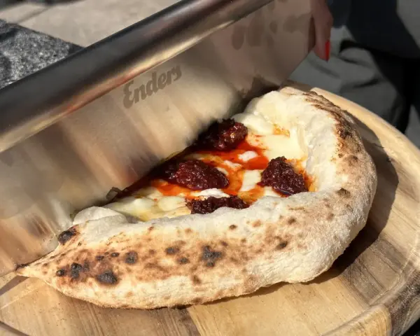Ein Messer schneidet ein Stück Pizza mit geschmolzenem Käse und würziger Tomatensauce. Der luftige pizzateig napoli ist perfekt gebacken.