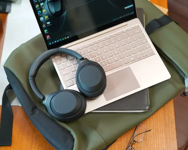 Słuchawki bezprzewodowe Sony leżą na laptopie, gotowe do połączenia. Dowiedz się, jak podłączyć słuchawki bezprzewodowe do laptopa, by cieszyć się dźwiękiem.