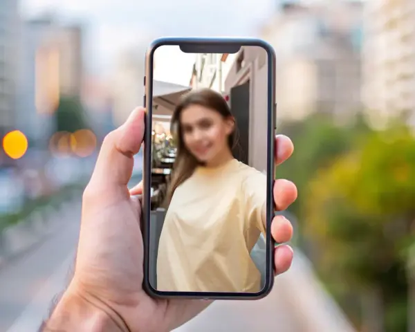 Chcesz wiedzieć, jak zamazać twarz na zdjęciu iPhone? Na ekranie telefonu widać rozmazaną twarz młodej kobiety.