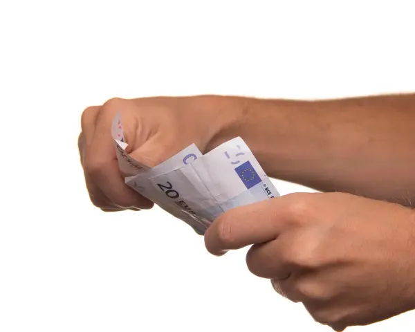 Dłonie trzymają banknoty euro. To może być symboliczne zawiadomienie o uchyleniu zajęcia, gdy pieniądze wracają do właściciela.