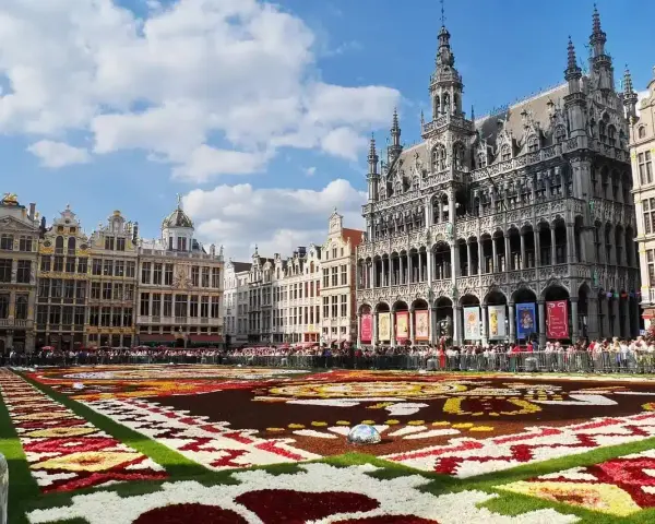 Grand Place, Brussels, with a vibrant flower carpet and ornate buildings under a blue sky.