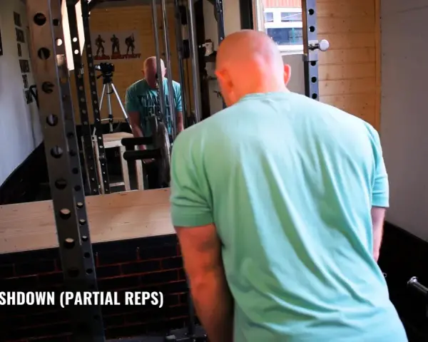 Man utför triceps pushdown med rep i gym.