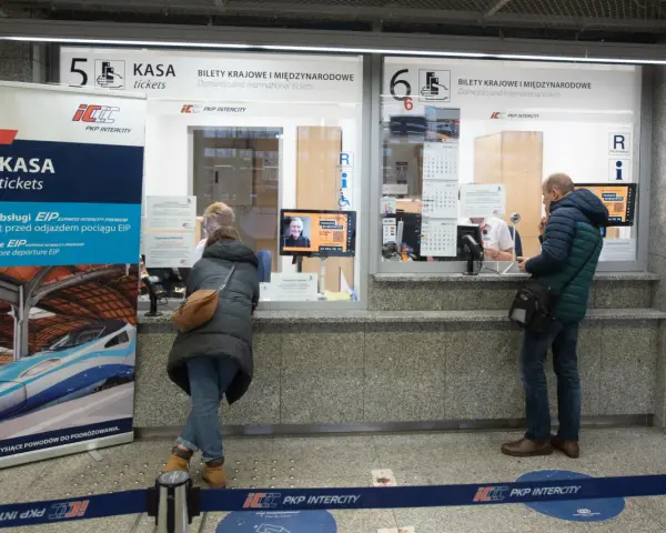 Kasa PKP Intercity w Poznaniu, gdzie kupisz bilety na pociąg do Warszawy. Ludzie stoją w kolejce do okienka.