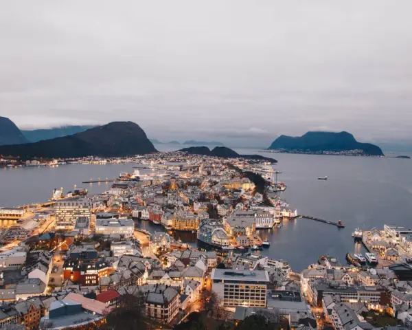 Vacker stad vid vattnet i Norge, med upplysta hus och berg i bakgrunden. En dröm att bila i Norge.
