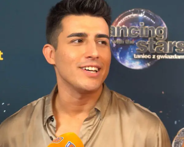 Filip Lato, w letniej stylizacji, udziela wywiadu. W tle logo "Dancing with the Stars".