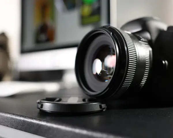Czarne body lustrzanki cyfrowej z obiektywem i dekielkiem na czarnym blacie. Zastanawiasz się dslr co to? To właśnie to!