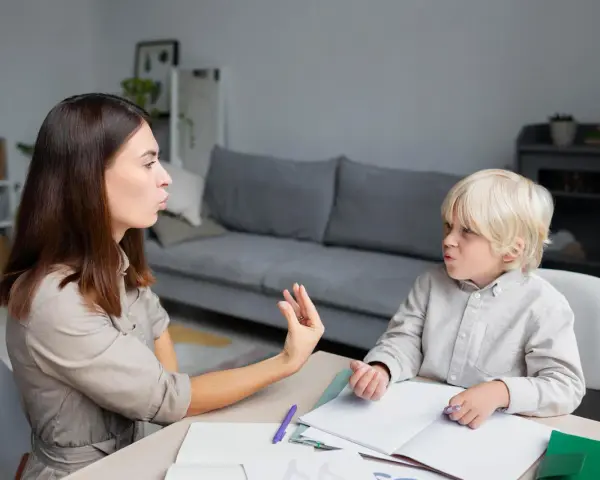 Terapeuta pracuje z dzieckiem, które ma orzeczenie o specjalnych potrzebach edukacyjnych, ćwicząc wymowę.
