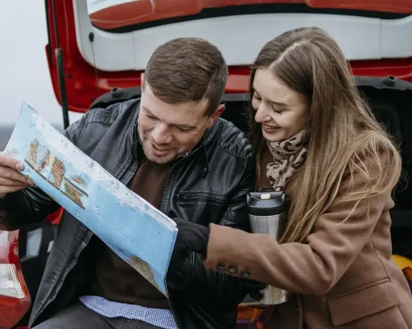 Para planować podróż i ubezpieczenie samochodu na wyjazd za granicę, para przegląda mapę.