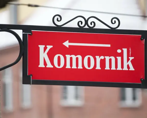 Czerwona tabliczka z napisem "Komornik" i strzałką w lewo. Pamiętaj, czego nie może zabrać komornik z mieszkania!