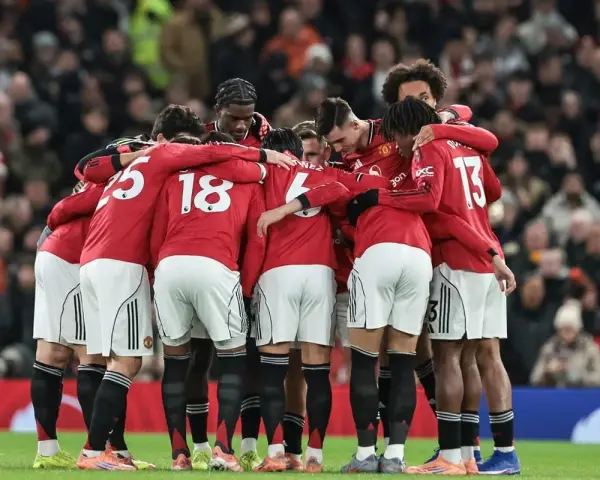 Piłkarze Manchesteru United w czerwonych strojach tworzą zwarty krąg, jednocząc się przed meczem. Ich wspólne united transfery budują ducha drużyny.