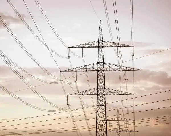 Linie energetyczne mwh przecinają niebo, tworząc geometryczny wzór na tle chmur.