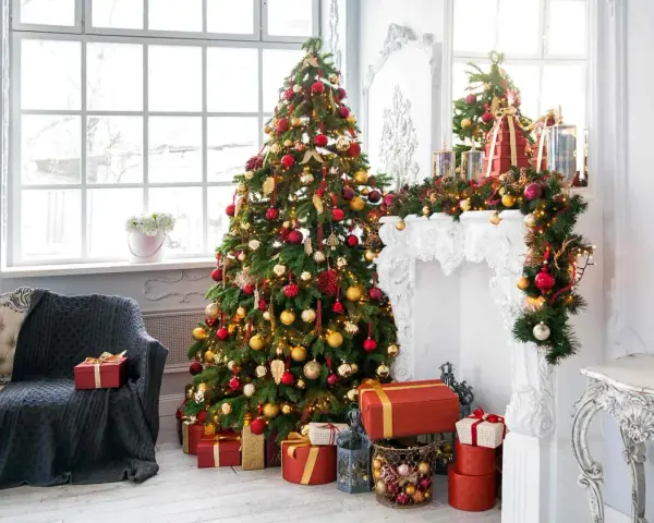 Un albero rosso, oro e bianco, addobbato con luci e palline, fa da protagonista in un salotto natalizio.
