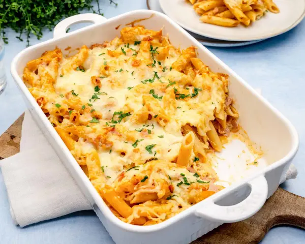 Herzhaftes Nudel Schinken Gratin mit geschmolzenem Käse und Petersilie, bereit zum Servieren.