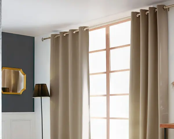 Eine schicke Gardinenstange anbringen, um die beige Vorhänge über dem Fenster zu befestigen. Dekorative Elemente wie Spiegel und Pflanzen ergänzen den Raum.