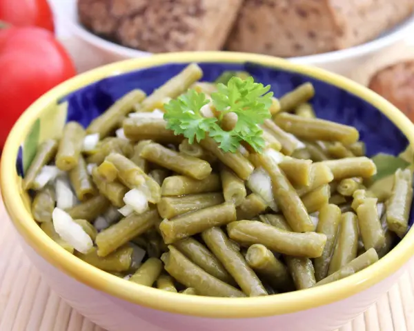 Bohnensalat rezept: Ein bunter Napf mit grünen Bohnen, Zwiebeln und Petersilie, bereit zum Servieren.