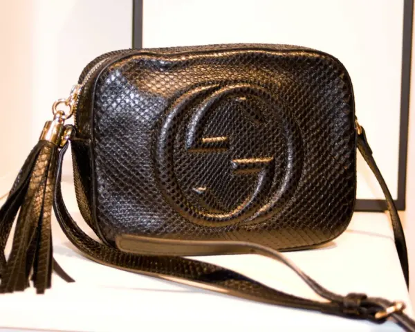 Czarna, pikowana torebka Gucci z wytłoczonym logo i frędzlami. Klasyczne, stylowe modele torebek Gucci.