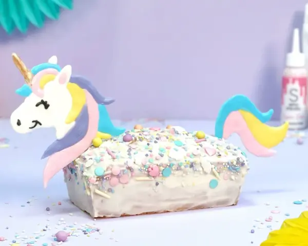 Ein magischer einhorn kuchen, verziert mit bunten Streuseln und einem süßen Einhorn-Topper, bereit für eine märchenhafte Feier.