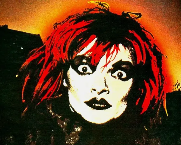 Visage intense d'une femme aux cheveux rouges et maquillage prononcé, évoquant l'esthétique d'un groupe allemand des années 90.