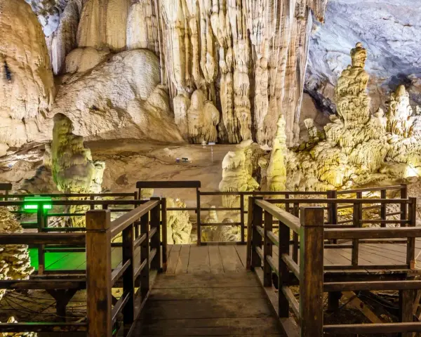 Drewniana kładka prowadzi przez wnętrze jaskini z imponującymi stalaktytami i stalagmitami, przypominającymi krajobraz najdłuższej jaskini w Polsce.