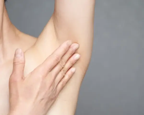 Hand berührt Achselhaut. Informationen zu Pickel unter Achsel Hausmittel.