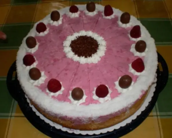 Eine köstliche Kokos Himbeer Torte, verziert mit Schokolade und frischen Himbeeren, bereit zum Genießen.