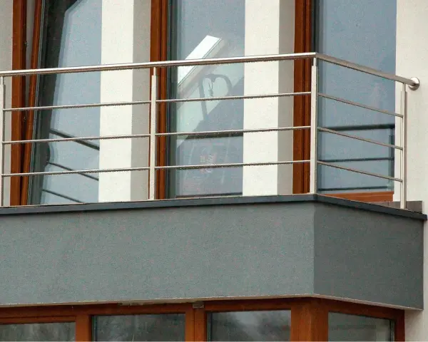 Nowoczesne mocowanie balustrady od czoła balkonu, wykonane ze stali nierdzewnej, z widocznymi czterema poziomymi prętami.