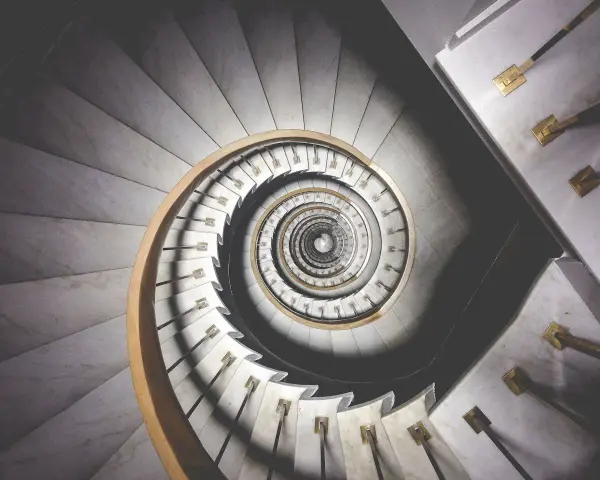 Kręcone schody z marmuru i drewna, tworzące spiralę przypominającą ciąg Fibonacciego w architekturze.