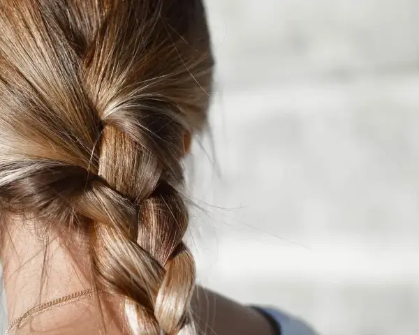 Gładki warkocz z blond włosów, idealny przykład, jak zmniejszyć porowatość włosów.