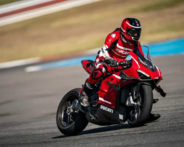 Motocyklista w czerwonym kombinezonie śmiga na torze wyścigowym na swoim czerwonym Ducati Panigale V4.