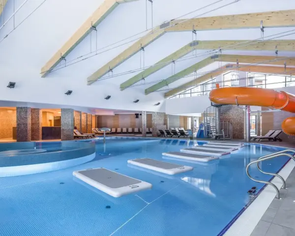 Wodne szaleństwo w hotelu z basenami w górach: zjeżdżalnia, jacuzzi i dmuchane wyspy na wodzie.