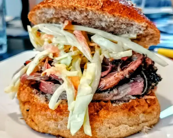 Sandwich con pulled pork, un classico della pulled pork ricetta, con pane integrale e insalata coleslaw cremosa.