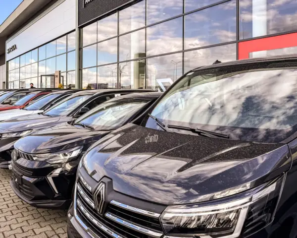 Rząd nowych samochodów na placu. W tle budynek salonu Dacia. Sprawdź autoplac opinie przed zakupem.