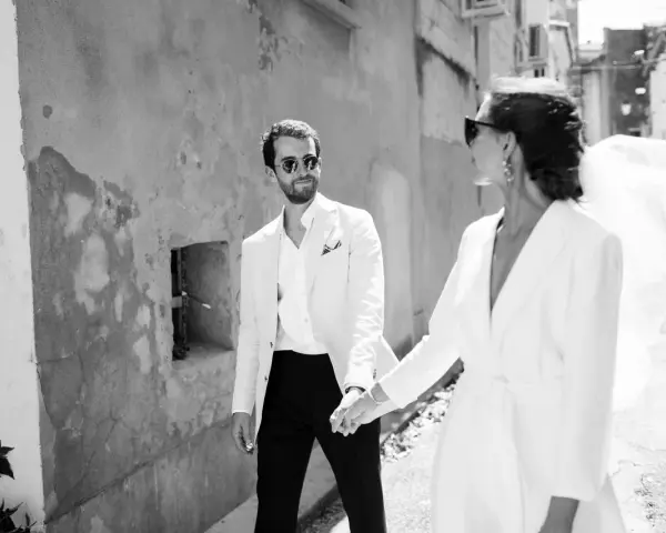 Un couple marié, main dans la main, traverse une ruelle. Ils pensent déjà aux démarches administratives après mariage au service public.