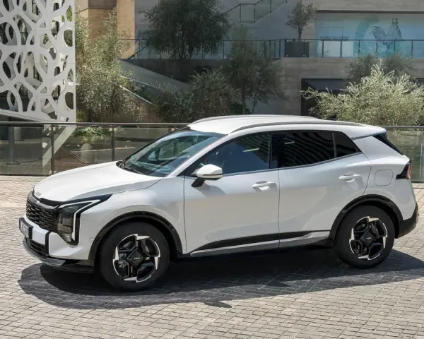 Biała Kia Sportage hybryda na tle nowoczesnej architektury. Stylowy SUV gotowy na miejskie wyzwania.