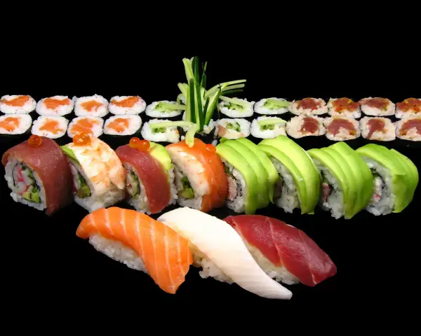 Różnorodne sushi: nigiri z łososiem, tuńczykiem i białą rybą, rolki z awokado, krewetką, tuńczykiem i ogórkiem. Idealne na początek nauki, jak jeść sushi.