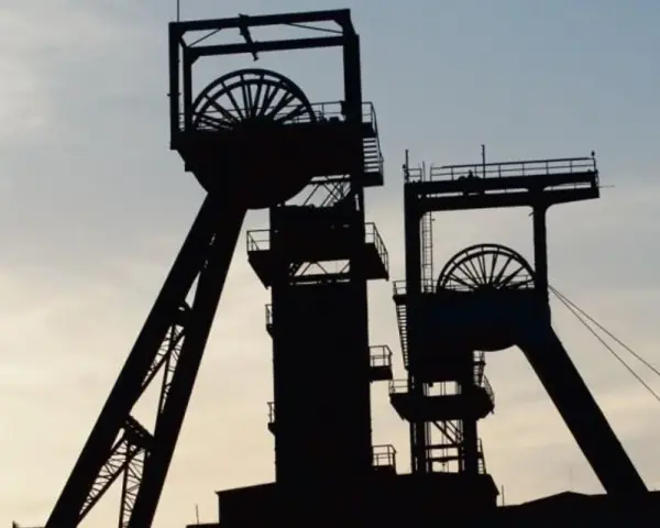 Dwie wieże szybowe kopalni węgla na tle nieba. Zastanawiasz się, ile zarabia górnik?