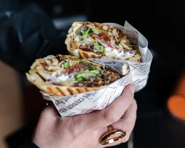 Pyszny kebab z Bukowiny Tatrzańskiej, pełen mięsa, warzyw i sosu, zawinięty w papier z gazetowym nadrukiem.