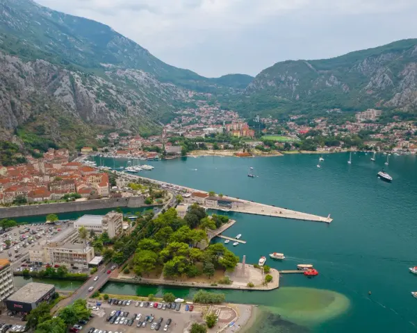 Widok na zatokę z górami w tle, miasto Kotor w Czarnogórze, z łodziami i budynkami.