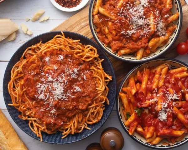 Pyszny obiad bez mięsa: spaghetti i penne w sosie pomidorowym, posypane parmezanem. Idealne dla wegetarian!