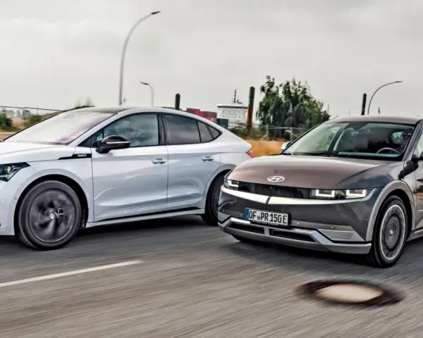 Dwa elektryczne samochody jadące obok siebie. Po prawej stronie ciemnoszary Hyundai Ioniq 5, po lewej biała Skoda. Zastanawiasz się nad ich zasięg?