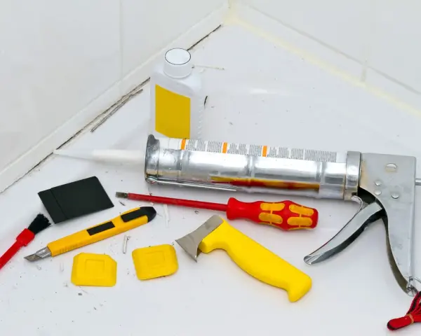 Attrezzi per la rimozione olio di silicone e sigillatura: pistola per silicone, taglierino, spatole, pennello e solvente.