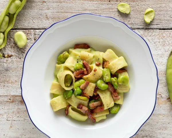 Piatto di pasta con fave fresche e croccante pancetta, un classico saporito.