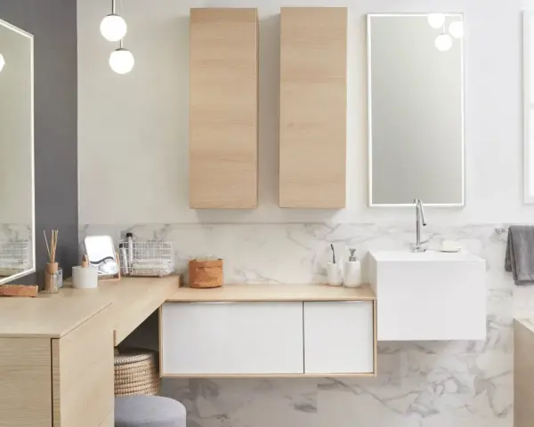 Salle de bain moderne avec un lavabo évier suspendu, des meubles en bois clair et un grand miroir éclairé.