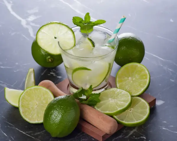 Orzeźwiająca Caipirinha przepis: świeże limonki, lód, mięta i drewniany muddler. Idealny drink na lato.