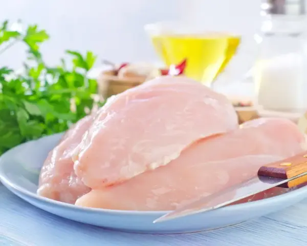 Surowe filety z kurczaka na talerzu, gotowe do przygotowania zdrowego posiłku. Sprawdź, jaki filet z kurczaka kcal ma w sobie!